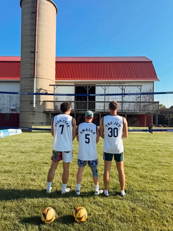 Volleyball team wearing custom numbered jerseys in front of a barn
